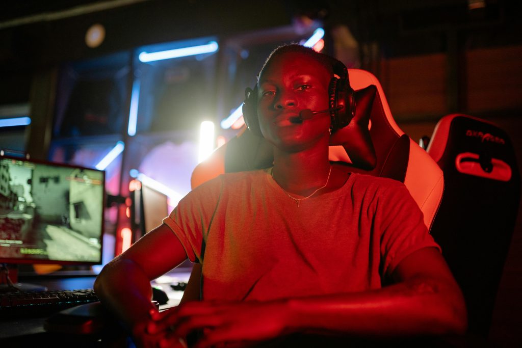 A focused gamer wearing a headset in a neon-lit room, ready for action.